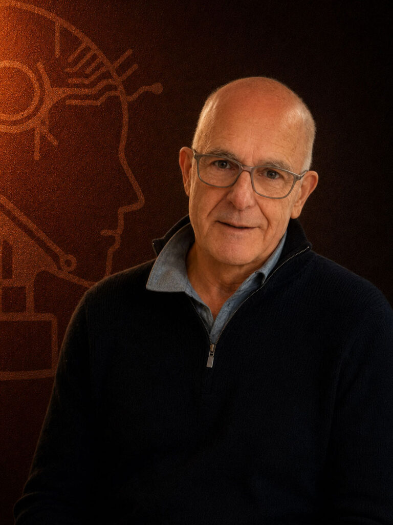 A middle-aged man with glasses and a dark sweater poses in front of an abstract brown background.
